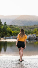 Full length rear view of woman standing by lake