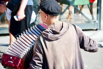 Man playing accordion while standing in city