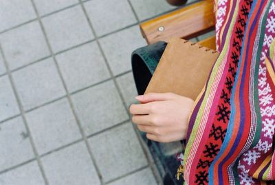 Cropped image of girl with book sitting on bench