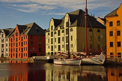 Buildings by river against sky in city