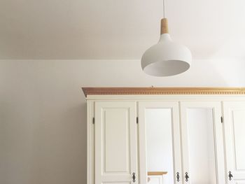 Low angle view of illuminated pendant lights hanging on wall at home