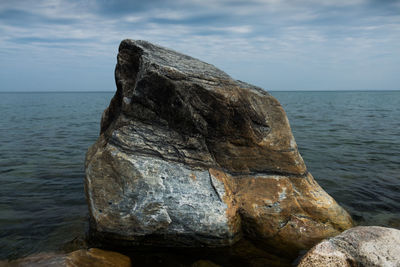 Rock formation on sea shore against sky