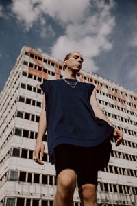 Low angle view of man standing against building and sky in city 