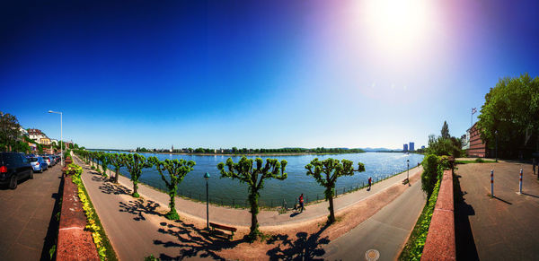 Panoramic view of road by sea against clear blue sky