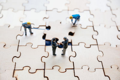 High angle view of figurines on wooden jigsaw puzzle