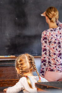 Rear view of woman sitting on wall