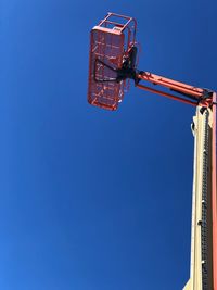 Low angle view of crane against clear blue sky
