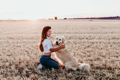 Side view of woman with dog on landscape during sunset