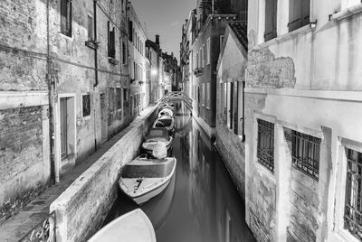 Boats moored in canal amidst buildings in city