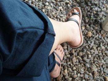Low section of man standing on pebbles