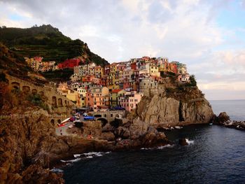 Illuminated cinque terre by sea against sky at dusk