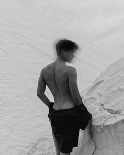 Rear view of shirtless man standing on snow