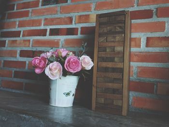 Pink roses in pot against brick wall