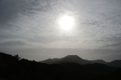 Silhouette of mountain range against cloudy sky