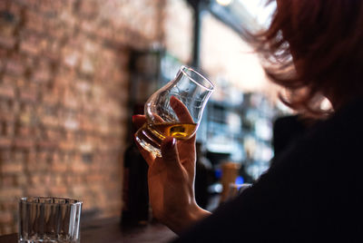 Cropped image of woman drinking whiskey at table in bar