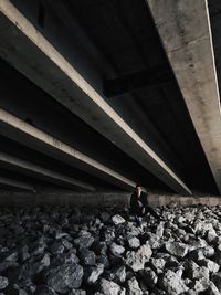 Woman sitting on rocks underneath of bridge