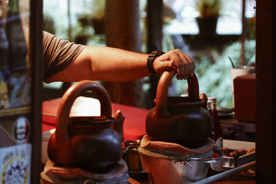 Cropped hand of person holding container on table