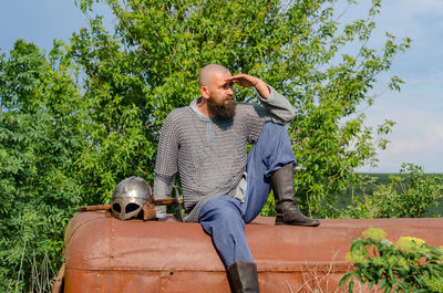 Emotional photo of medieval viking in metal chain mail, looking anxiously into distance. cloudy sky