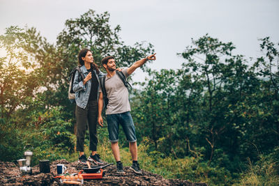 Full length of young couple standing against trees