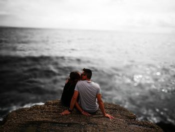 Couple kissing at beach against sky