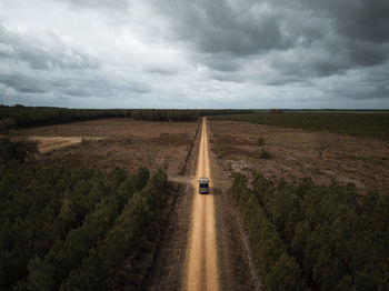 Road amidst field against sky