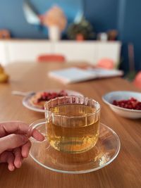 Close-up of hand holding drink on table