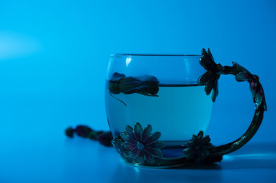 Close-up of blue glass on table against sea