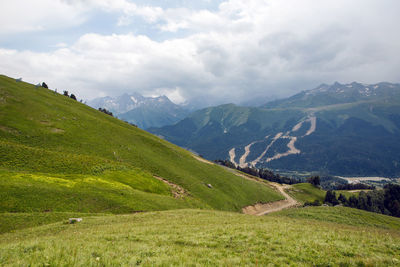 Green slope of a high mountain during a thunderstorm with clouds in the sky