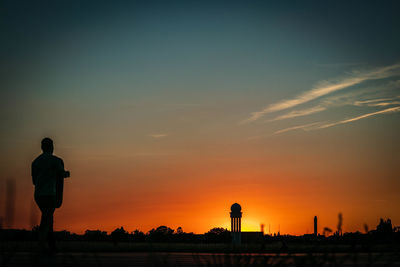 Silhouette man standing against orange sky