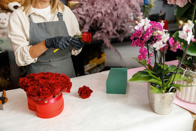 Midsection of woman picking flowers on table