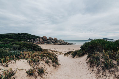 View of calm beach against cloudy sky