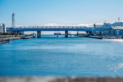 Bridge over sea against clear blue sky