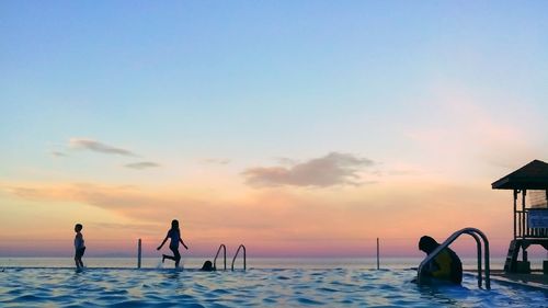 People at infinity pool during sunset