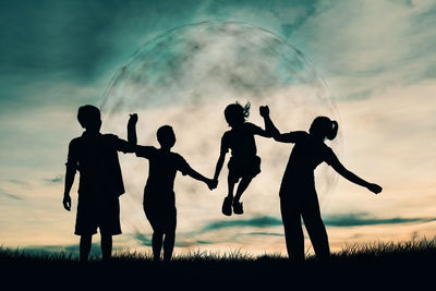 Silhouette family enjoying while standing on grassy field against sky during sunset