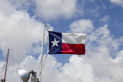 Low angle view of flags against cloudy sky