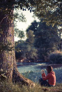 Woman using mobile phone while sitting on field