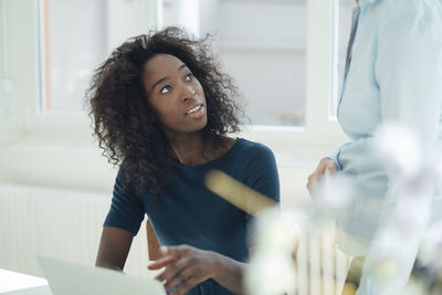 Young businesswoman discussing with colleague in office