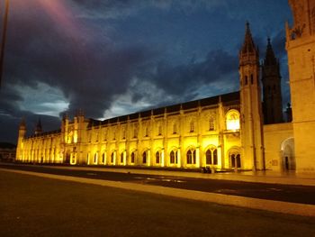 Illuminated building against cloudy sky at night