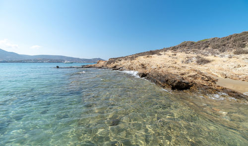 Surface level of beach against clear blue sky