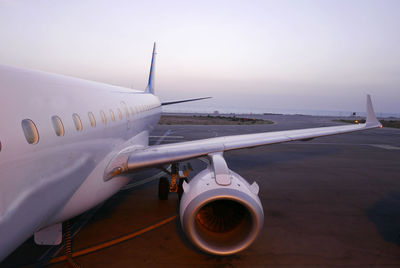 Airplane on airport runway against sky during sunset