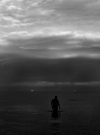Silhouette men in sea against sky
