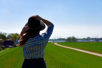 Rear view of woman standing on field against clear sky