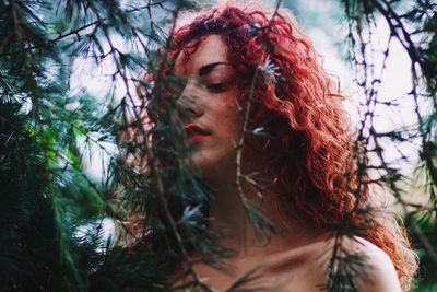 Close-up portrait of young woman with tree