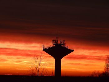 Low angle view of silhouette tower against dramatic sky during sunset