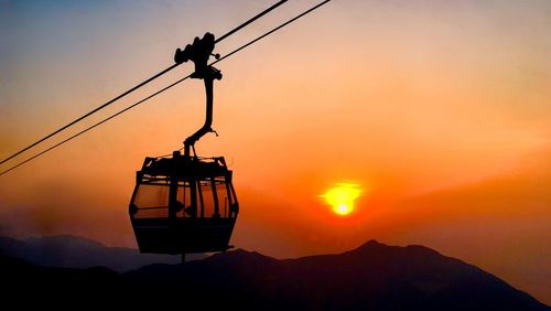 Overhead cable car against sky during sunset