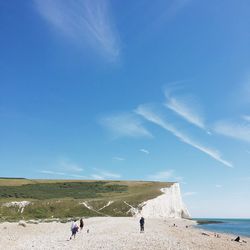 Women at beach against blue sky