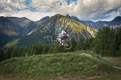 Man riding bicycle on mountain against sky