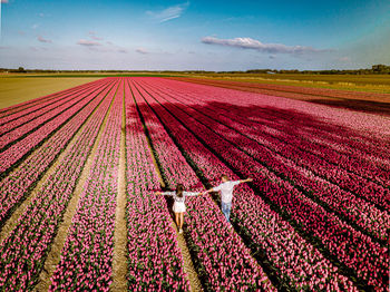 Rear view of couple standing amidst flowering plants on field