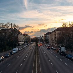 Road passing through city at sunset