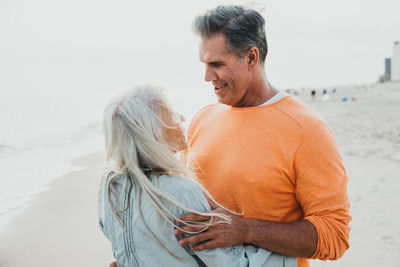 Side view of smiling couple embracing at beach
